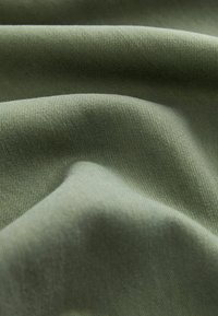 Zöld pamutanyag sima textúrával és diszkrét stretch tulajdonsággal, finom bordázott mintával. Különféle textil alkalmazásokhoz alkalmas.
