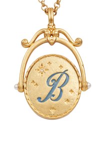 Zlatý náhrdelník s príveskom v tvare modrého písmena "B" na textúrovanom kruhovom základe. Obsahuje malé hviezdy a perly, s ozdobným kovovým zdobením.