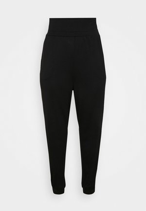 Pantalones negros de cintura alta y corte cónico con puños elásticos y discretos bolsillos laterales, exhibidos sobre un fondo blanco liso.