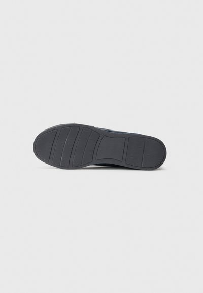 Talpa unei pantofi eleganți pentru bărbați de culoare albastru închis, cu modele de striații și netede orizontale, expusă pe un fundal gri deschis simplu.