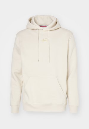 Beige hettegenser laget av myk bomullsblanding. Har en frontlomme, snor i hetten og gullbroderi av logoen på brystet.