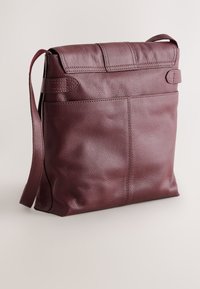 Bordeauxrode leren crossbodytas met een gestructureerde afwerking, klepsluiting, enkele schouderriem en achterzak. Eenvoudige rechthoekige vorm.