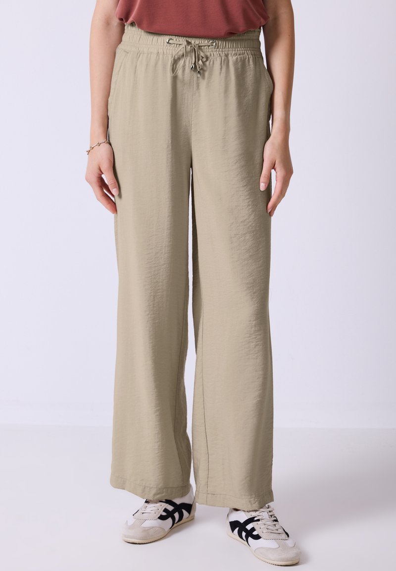 Lichte, beige wijde broek met een elastische tailleband en trekkoord, voorzien van zijzakken en een gestructureerd materiaal.