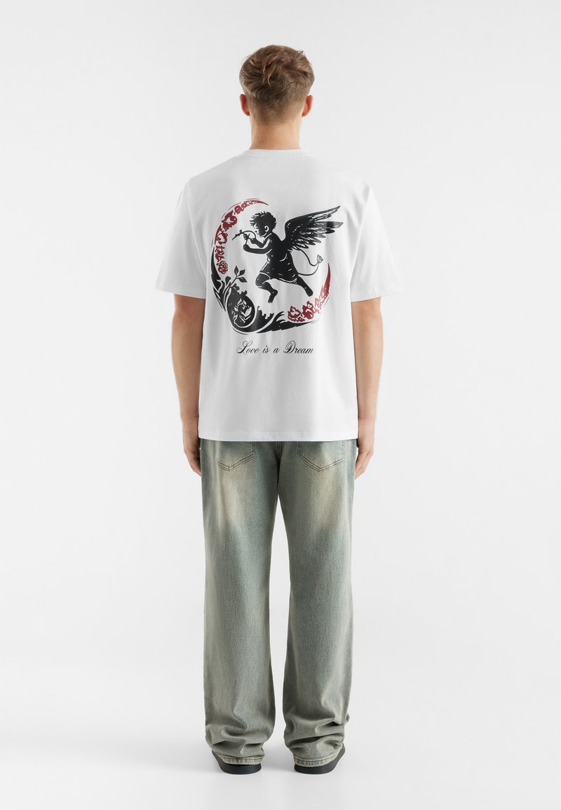 White cotton t-shirt features a black and red graphic design on the back, depicting an angel with text "Love is a Dream." Casual fit.