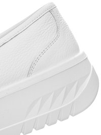 Close-up of the heel and sole of a white leather sneaker with textured pattern and thick, ridged outsole.