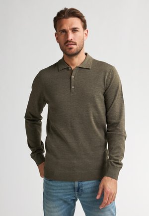 Olijfgroene poloshirt met lange mouwen en een kraaghals, drie-knopen placket en ribgebreide manchetten en onderkant. Stof lijkt zacht van textuur.