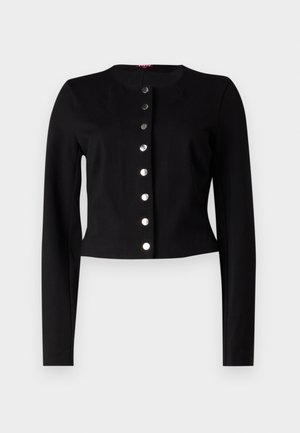 Melnā īsā kardigāna ar apaļu kakla izgriezumu, garām piedurknēm un septiņām metāliskām pogām priekšpusē. Gluda tekstūra.