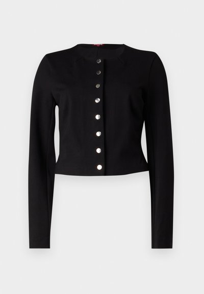 Mustan lyhyen mallin neuletakkia, jossa on pyöreä kaula-aukko, pitkät hihat ja seitsemän metallista napin kiinnitystä edessä. Sileä pinta.