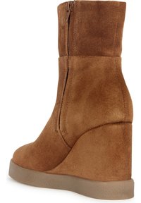 Botte à plateforme compensée en daim marron avec une finition lisse, fermeture éclair latérale et semelle plateforme texturée. Le design présente un bout arrondi et une tige haute.