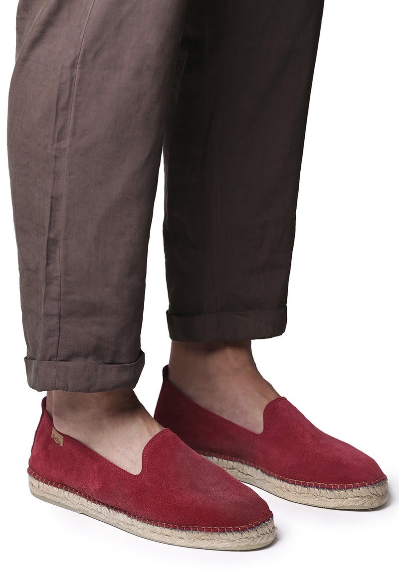 Espadrilles rojas de ante con suela de cuerda de yute, que cuentan con un diseño sin cierre y se combinan con pantalones marrones cropped.