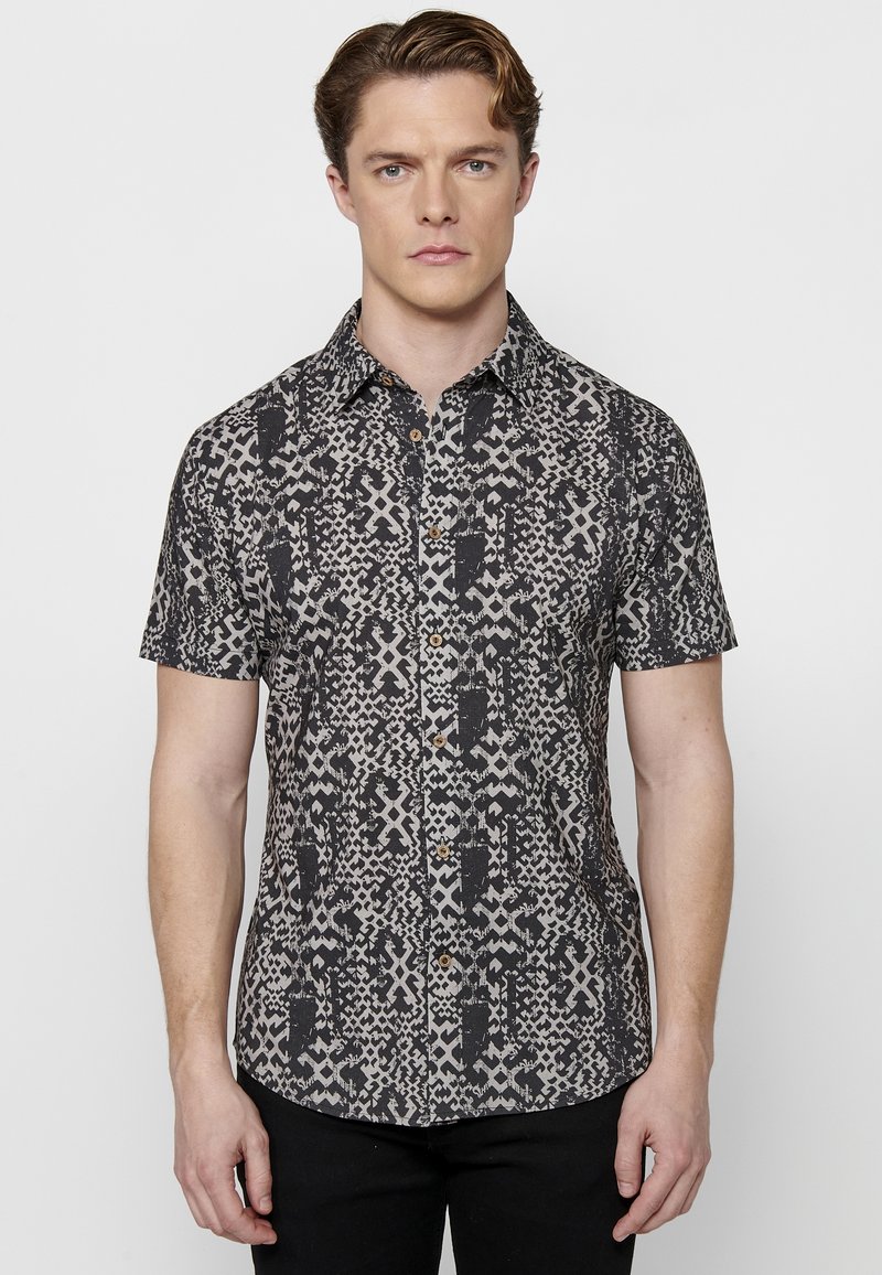 Korte mouwen button-up shirt met een zwart en beige geometrisch patroon, voorzien van een kraag en knopen in houttint.