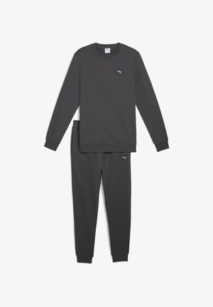 Costum de trening gri închis, confecționat dintr-un material moale; tricou cu mâneci lungi și pantaloni tapered cu manșete. Prezintă un mic logo Puma, de culoare neagră, pe ambele piese.