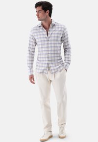 Himmelblaues und weißes karierter Hemd mit langen Ärmeln und Kragen, kombiniert mit cremefarbenen Hosen und weißen Sneakers, keine Muster auf den Hosen.