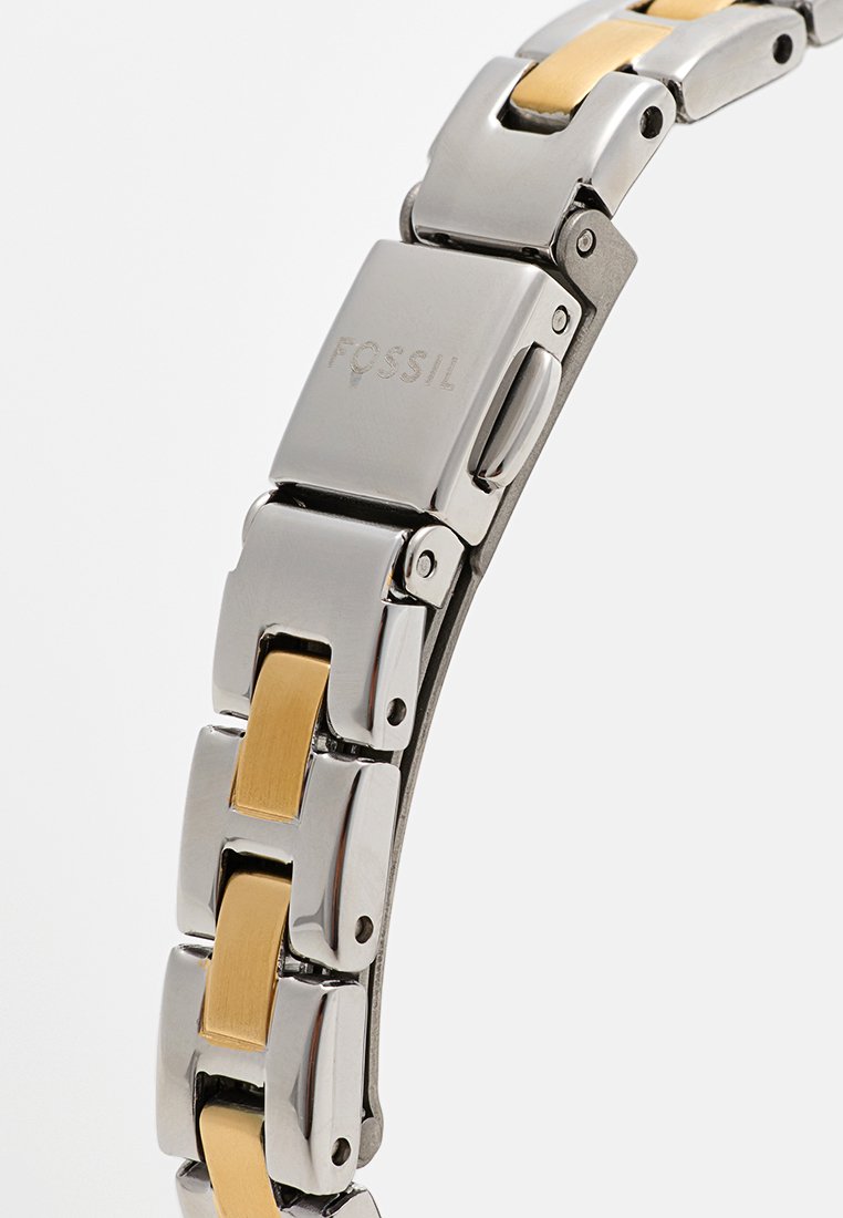 Bracelet de montre en métal alliant acier inoxydable argenté et accents dorés, avec une finition polie et un design à maillons.