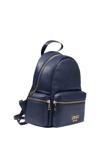 Zaino in pelle blu navy con design arrotondato, due tasche frontali con zip, accessori in tono oro e una maniglia superiore. Decorato con dettaglio del logo.