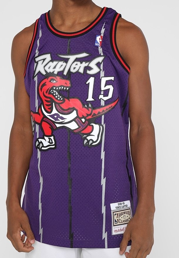 Man som bär en lila Toronto Raptors baskettröja med nummer 15 och en röd dinosaurielogo på framsidan.