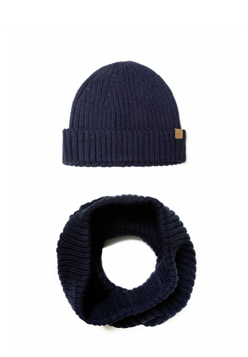 Navyblaue Strickmütze mit geripptem Muster und einem kleinen Lederetikett; passender navyblauer Strick-Infinity-Schal mit ähnlichem Rippdesign.