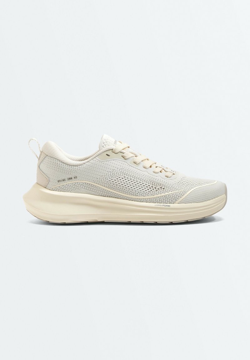Baskets légères beige avec dessus en mesh, fermeture à lacets, semelle épaisse et rembourrée, et languette au talon, présentées de profil sur un fond uni.