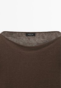 Close-up of a brown knitted sweater neckline with a Massimo Dutti label sewn inside, made in China.