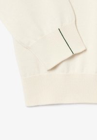Cremefarbenes Strickpullover mit einem gerippten Bündchen und einem grünen Akzentstich. Die Textur ist glatt mit einem leichten Stretch.