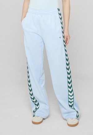 Lyseblå joggebukser med avslappet passform, med et grønt fiskebensmønster på sidene og sidelommer. Myk, glatt tekstur.