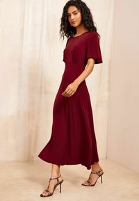 Rochie midi burgundă cu mâneci scurte, din țesătură moale și fustă evazată. Asortată cu sandale cu toc înalt cu imprimeu leopard.