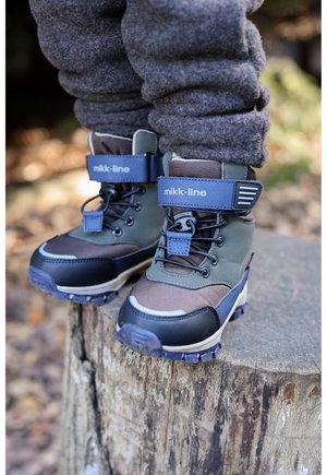 Waterdichte kinderschoenen in bruin, grijs en zwart, met een gevoerde kraag, verstelbare band en gestructureerde zolen voor grip.