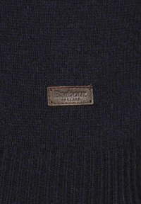 Navy gestrickter Pullover mit Rippstruktur, ausgestattet mit einem braunen Lederlabel, das auf der Vorderseite die Markenbezeichnung zeigt.
