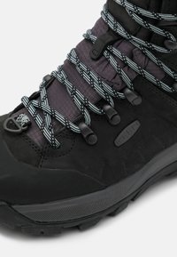 Botas de senderismo negras, resistentes, con materiales de malla y sintéticos, que presentan cordones reflectantes a rayas, ojales y una suela de goma texturizada.