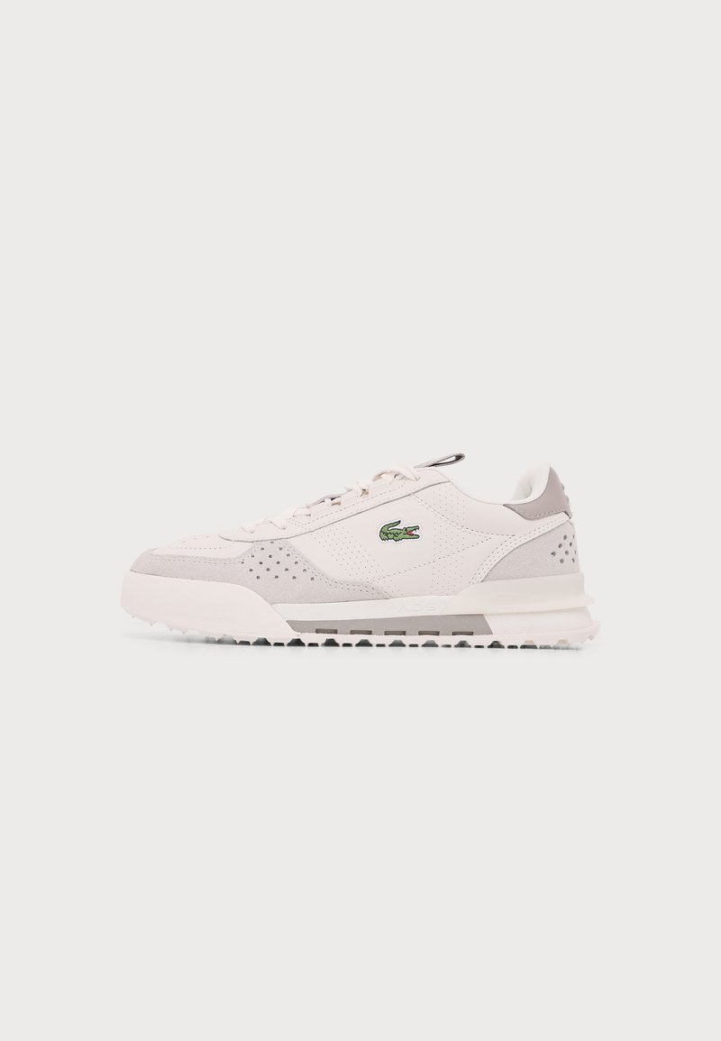 Baskets Lacoste blanches et gris clair avec logo crocodile vert, panneaux latéraux perforés et semelle en caoutchouc texturée.