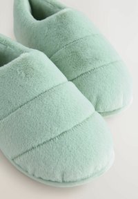 Light green plush slippers with a quilted design and soft texture. Rounded toe and padded sole for comfort.