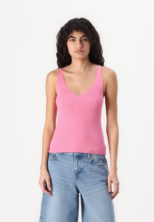 Lyserød ribbet tanktop med en dyb V-hals og brede stropper, parret med lyseblå afslappede jeans. Stoffet ser blødt og strækbart ud.