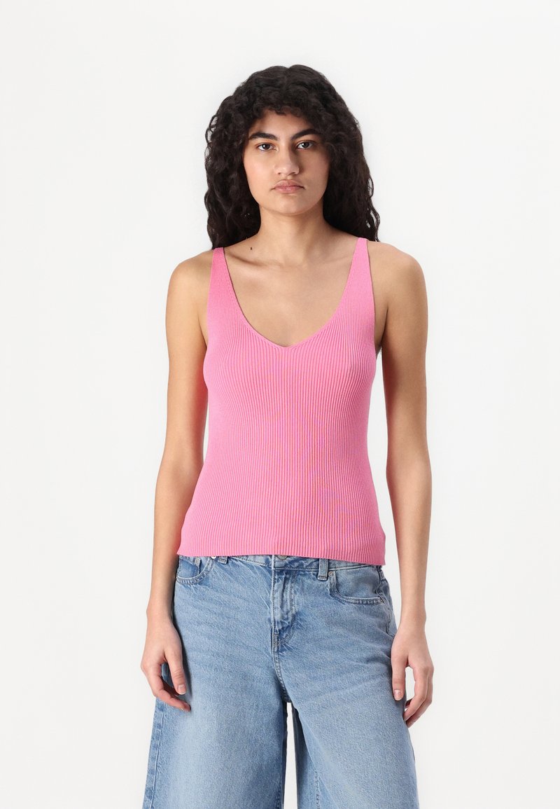 Rosa ribbet tanktopp med dyp V-hals og brede stropper, parret med lyseblå, avslappede jeans. Stoffet ser mykt og elastisk ut.