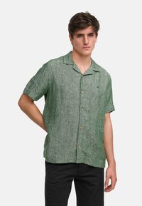 Camicia verde a maniche corte realizzata in tessuto testurizzato, con chiusura a bottoni, colletto morbido e un motivo discreto.