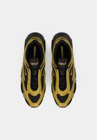 Μαύρα και κίτρινα αθλητικά παπούτσια με κομψό σχέδιο, featuring υφή στο πάνω μέρος, δίχτυ αεραγωγών και σήμανση Air Max.