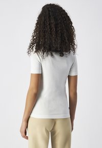 Top fitted a maniche corte grigio chiaro con texture a costine, tessuto morbido e semplice scollatura rotonda, abbinato a pantaloni beige.