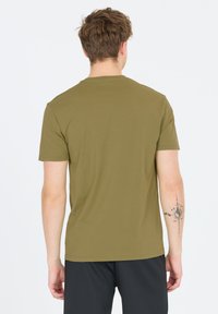 Vihreä puuvillapaita, jossa on lyhyet hihat ja pyöreä kaula-aukko, esitetty takaa. Paidassa on sileä pinta eikä näkyviä kuvioita.