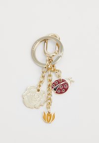 Porte-clés doré avec trois breloques : une rose crème, une coccinelle bordeaux avec des taches noires, et une tulipe orange sur de délicates chaînes.