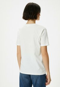Hvid bomulds t-shirt med korte �ærmer, rund hals, glat tekstur og en afslappet pasform. Bagfra viser den et simpelt design uden mønstre.
