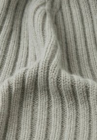 Tessuto a maglia a coste di colore grigio chiaro con una texture morbida, caratterizzato da strisce verticali prominenti e un aspetto leggermente peloso.