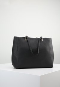 Svart tote-väska med slätt, texturerat syntetmaterial, rektangulär form, dubbla handtag, silverfärgade metalldetaljer och inga synliga logotyper.