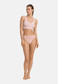 Ljust rosa sömlös sport-bh med breda axelband, i kombination med matchande högmidjade bikiniunderdelar. Slät yta, minimalistisk design.