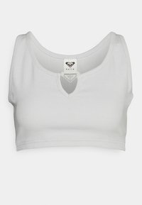 Top curto branco com nervuras, com um decote arredondado e um recorte em forma de olho-chave no centro. Possui uma etiqueta de logotipo na área do pescoço.
