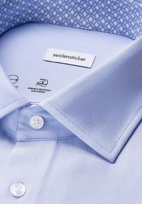 Lichtblauw overhemdd met een klassieke kraag en witte knopen, met een contrasterende gemusterde binnenkraagvoering.