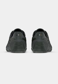 Paire de baskets noires décontractées vues de dos, avec le logo BOSS embossé sur les semelles des talons.