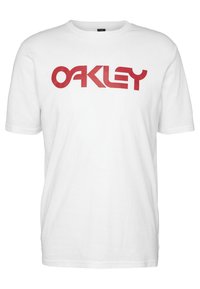 Bílé bavlněné tričko s velkým červeným logem "OAKLEY" na přední straně. Krátké rukávy a kulatý výstřih. Klasický střih.