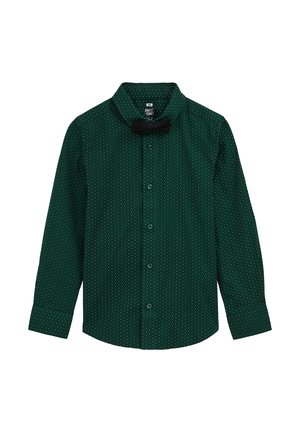 Zielona koszula z długim rękawem w białe kropki, guziki z przodu oraz spiczasty kołnierzyk. Posiada czarną muszkę przy dekolcie.