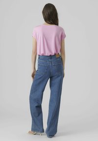 Pink short-sleeve top paired with high-waisted blue wide-leg jeans, featuring dual back pockets and a tailored waistline.
