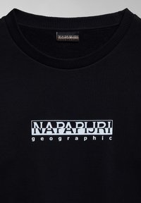 Sudadera negra con cuello redondo acanalado y un logo impreso en blanco que dice "NAPAPIJRI geographic." Textura suave.