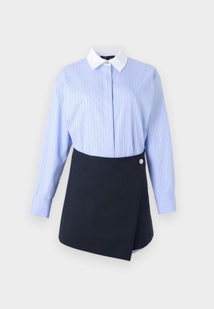 Chemise à manches longues bleu à fines rayures avec col blanc, associée à une jupe portefeuille asymétrique noire avec un détail de bouton argenté.